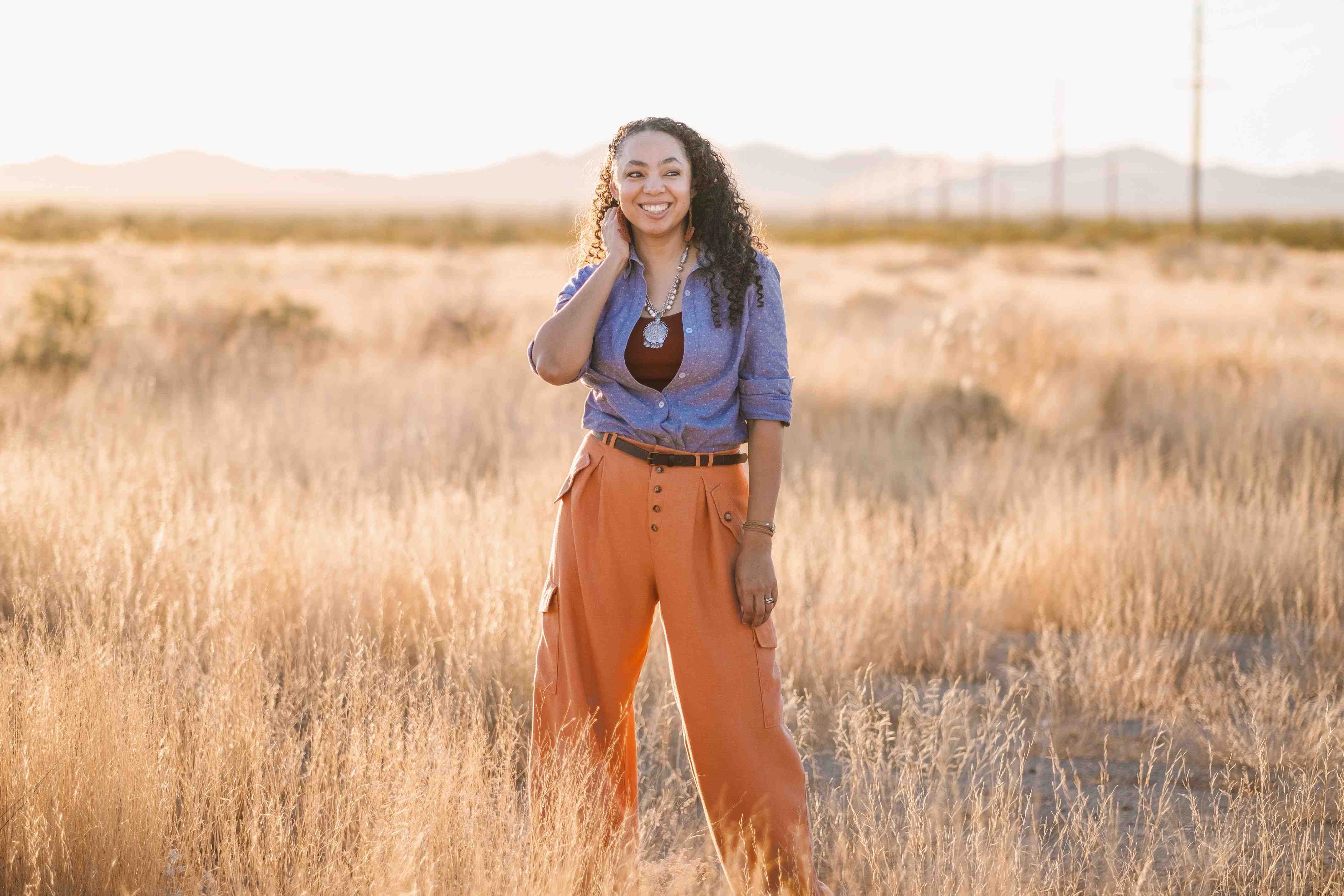 Maker of CocoMayStyle, Ilah, standing in a field wearing a purple shirt and orange pants.