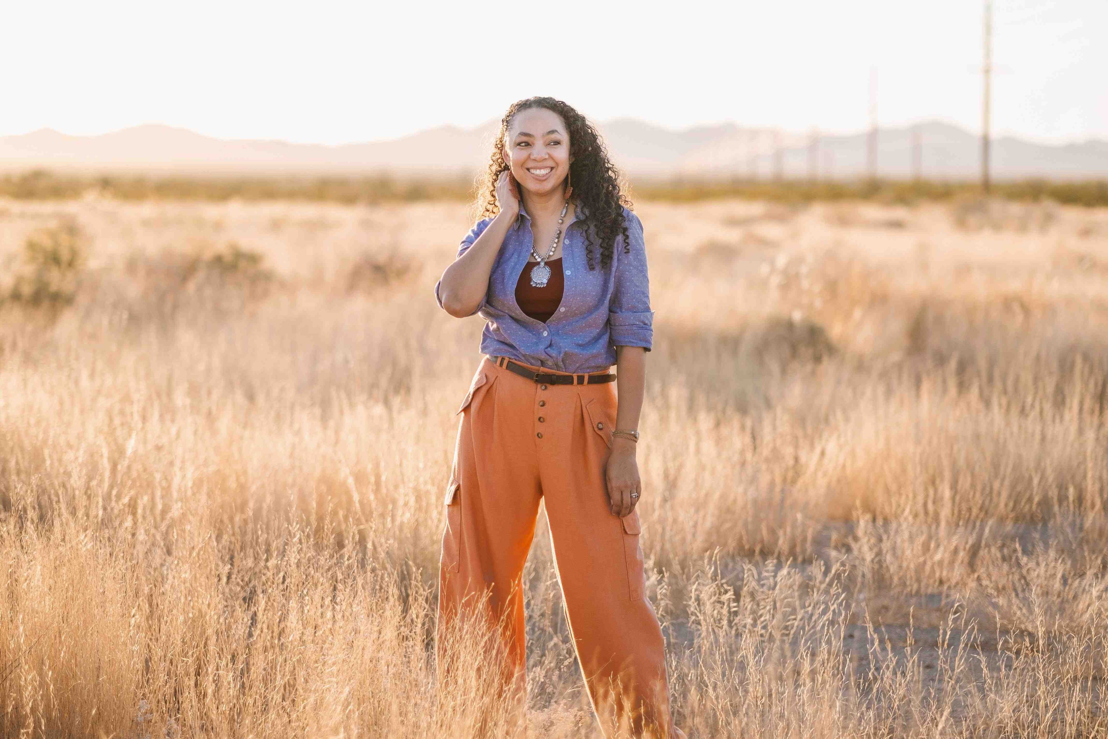 Maker of CocoMayStyle, Ilah, standing in a field wearing a purple shirt and orange pants.