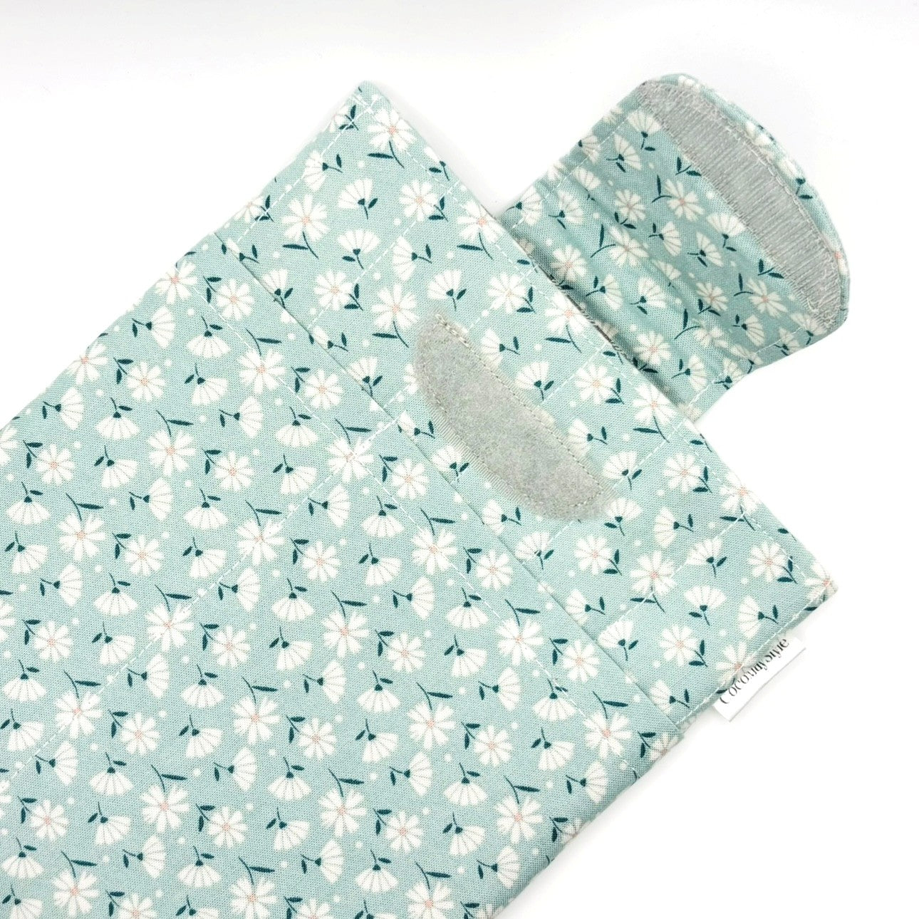 E-Reader sleeve with floral patterned fabric on a light blue background showing open velcro flap