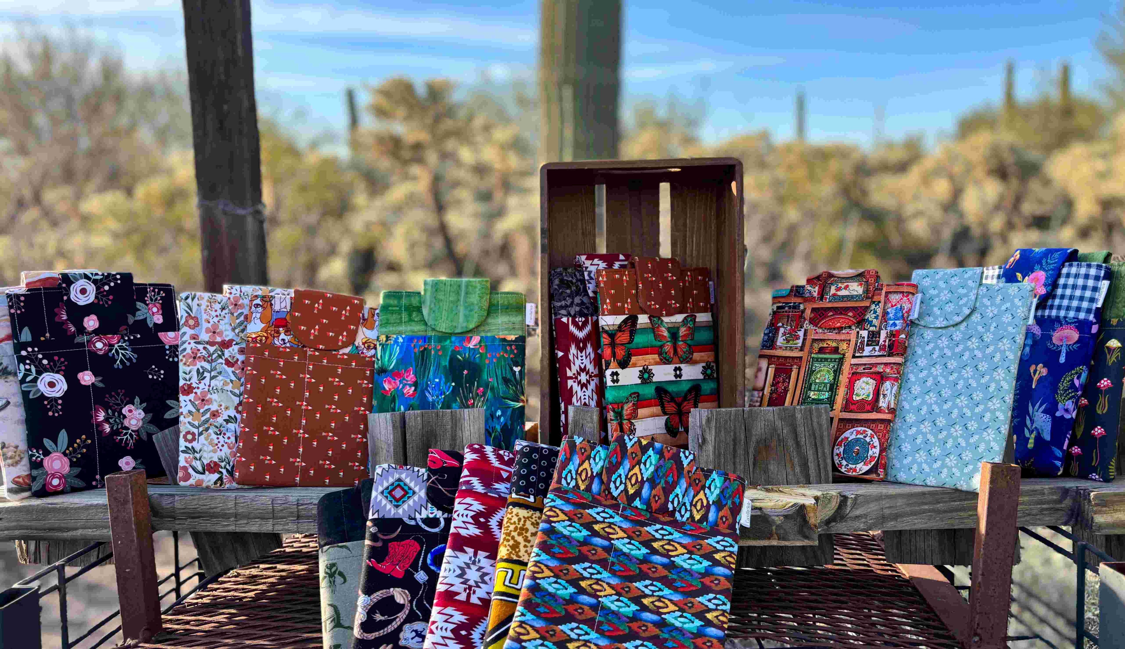 Colorful fabric e-reader sleeve bags displayed outdoors with a desert landscape in the background