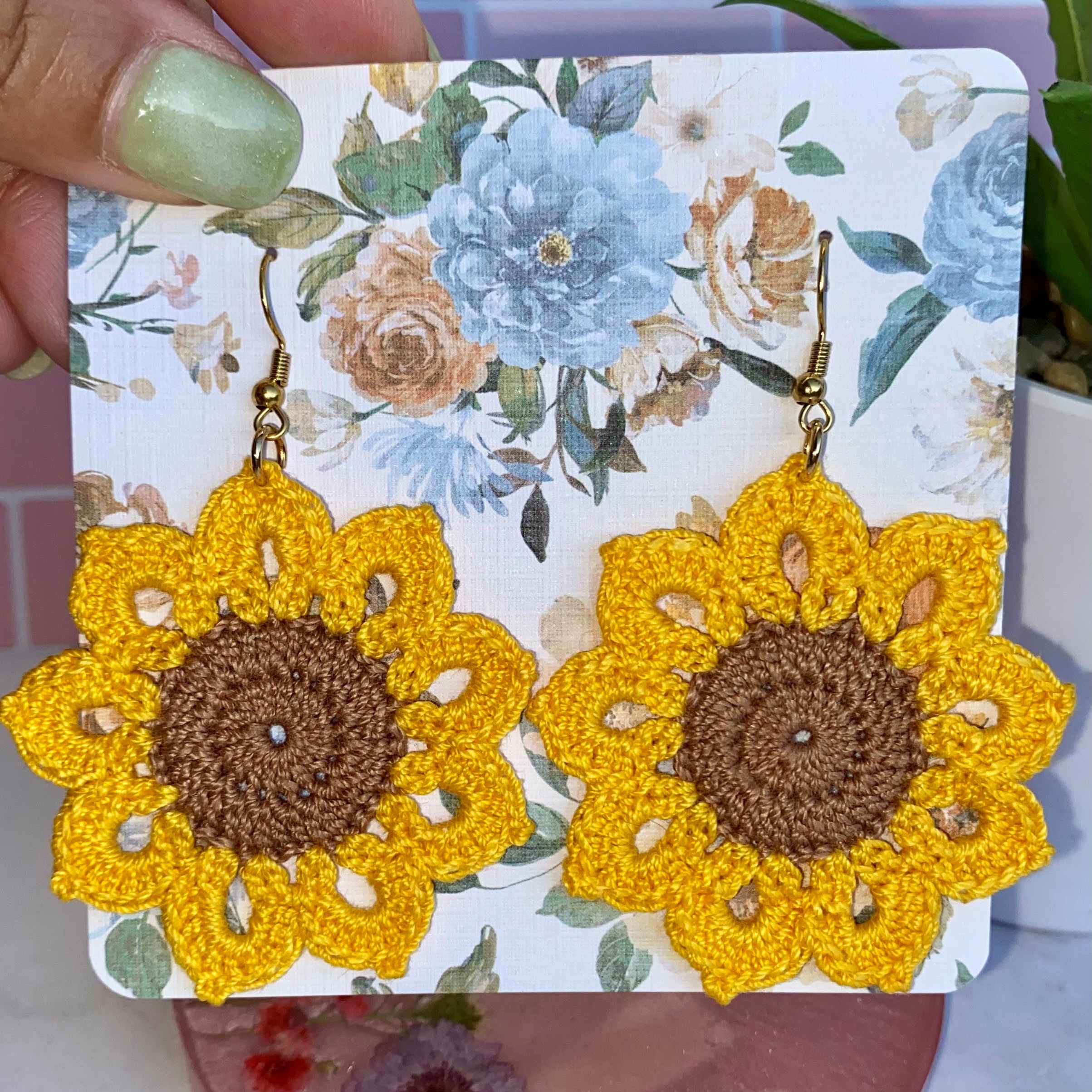 Crocheted yellow sunflower earrings with gold hooks on a floral backing card