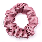 Dusty pink satin scrunchie on a white background