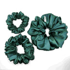 Dark green satin scrunchies on a white background