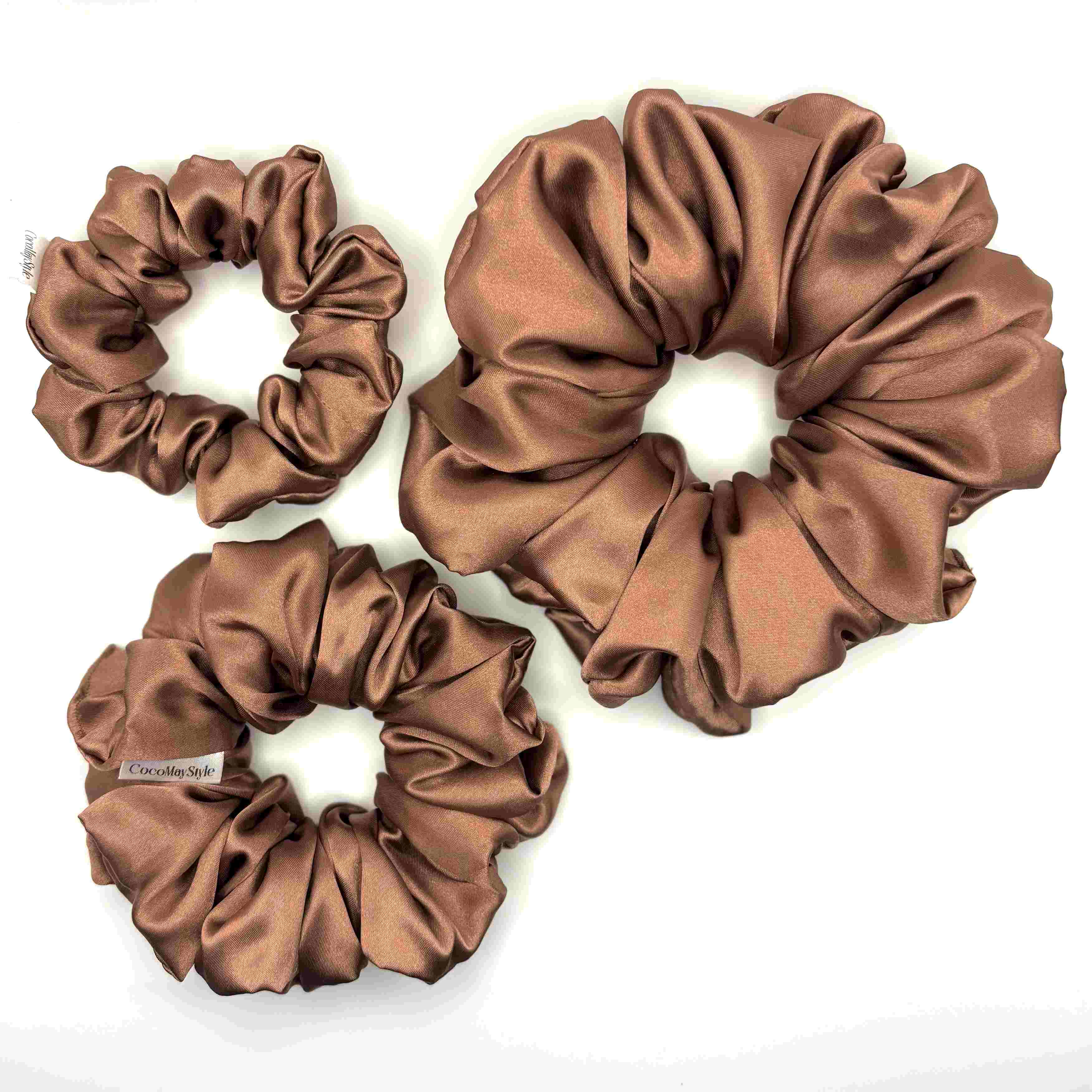 Light brown/tan satin scrunchies on a white background