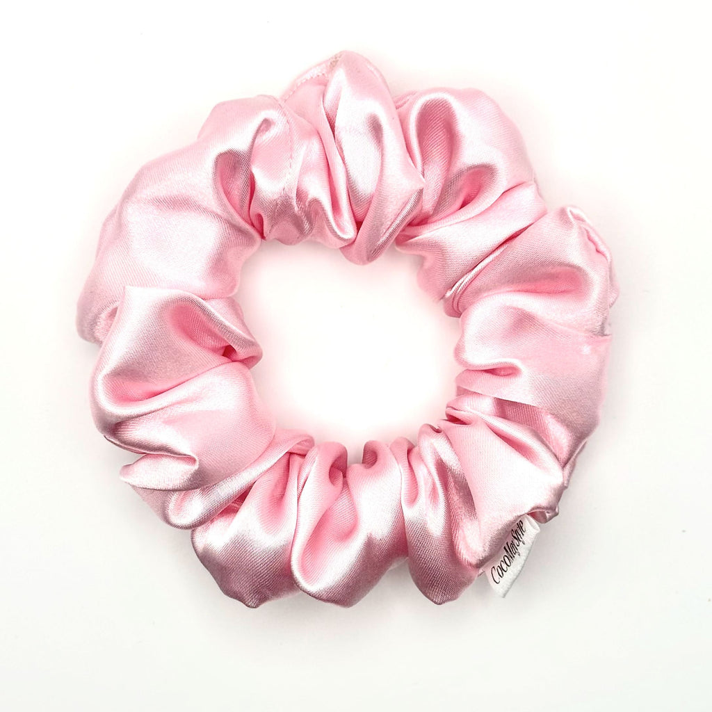 Light pink satin scrunchie on a white background