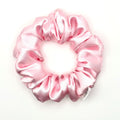 Light pink satin scrunchie on a white background