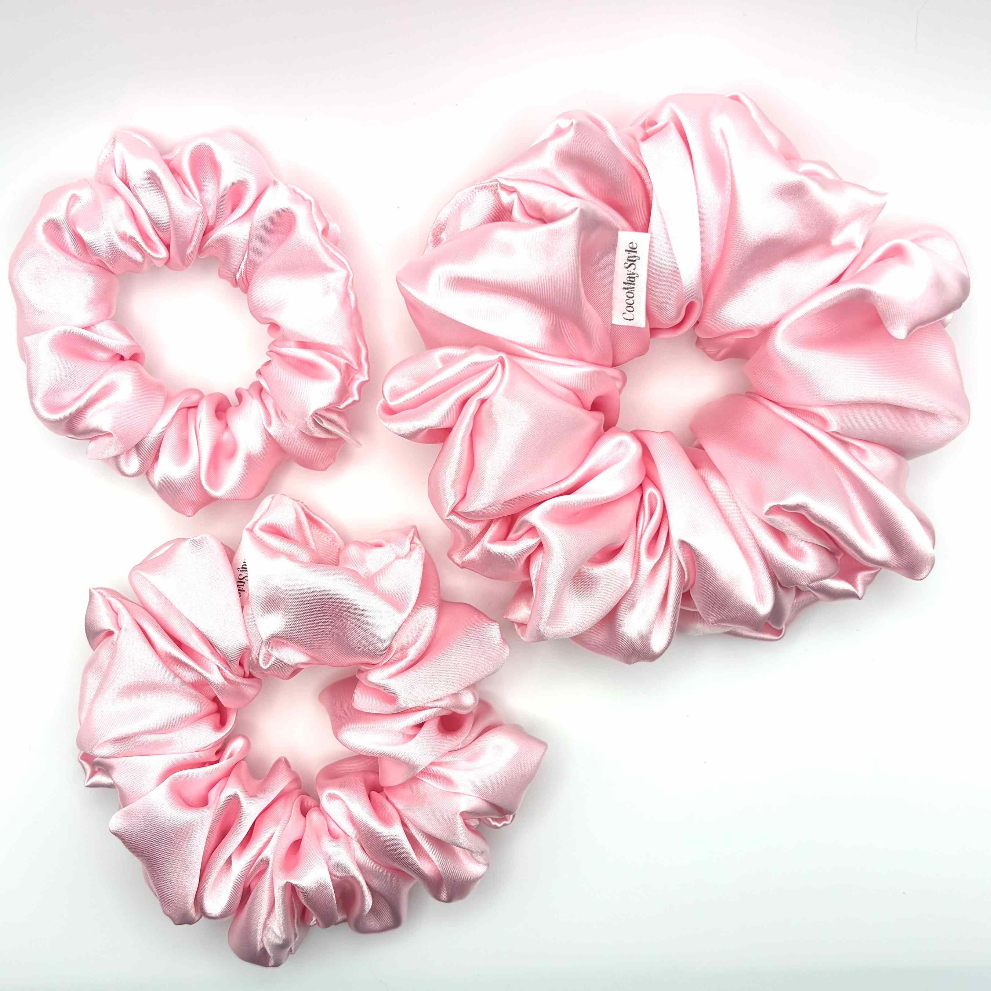 Light pink satin scrunchies on a white background
