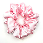Light pink satin scrunchie on a white background
