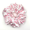 Pink and white satin scrunchie with bow pattern on a white background