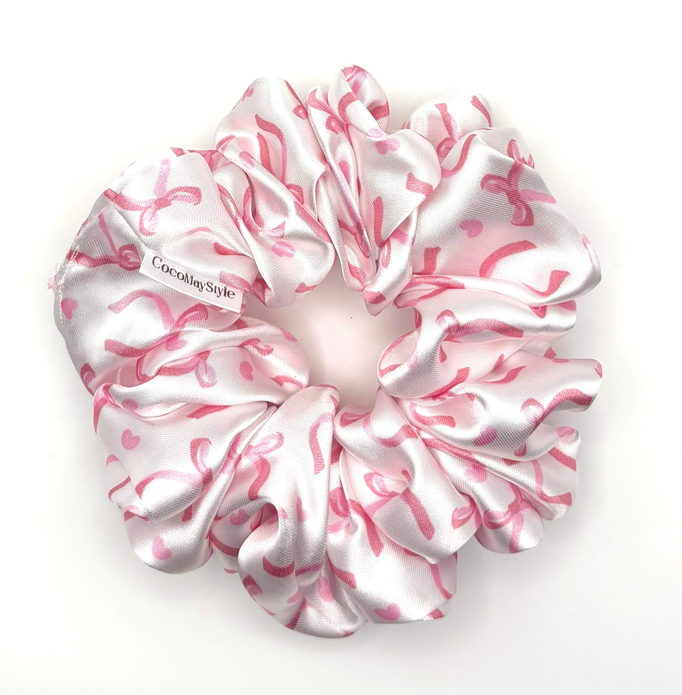 Pink and white satin scrunchie with bow pattern on a white background