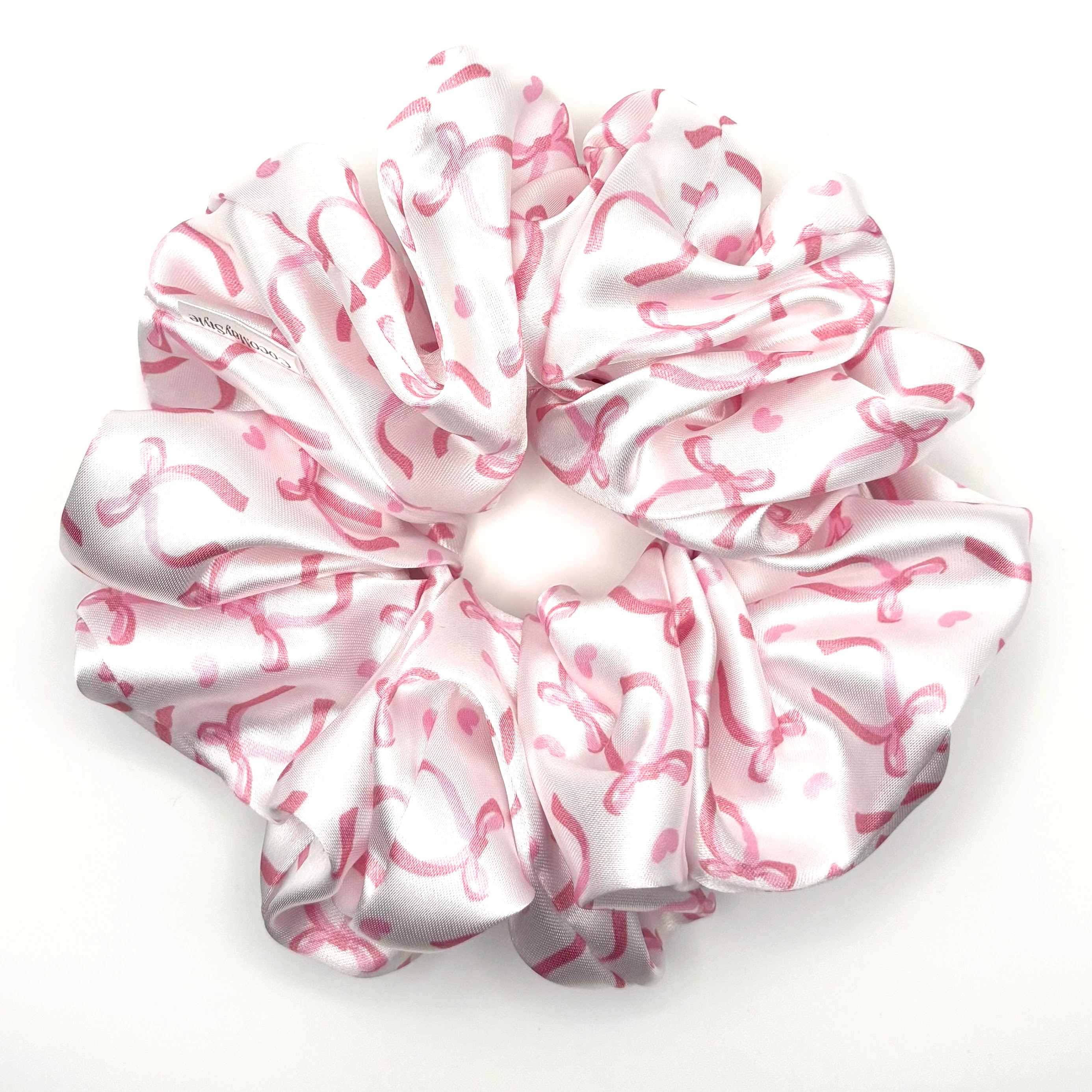 Pink and white satin scrunchie with bow pattern on a white background