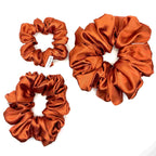 Orange satin scrunchies on a white background
