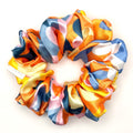 Colorful patterned satin scrunchie on a white background