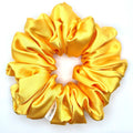 Yellow satin scrunchie on a white background
