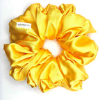 Yellow satin scrunchie on a white background