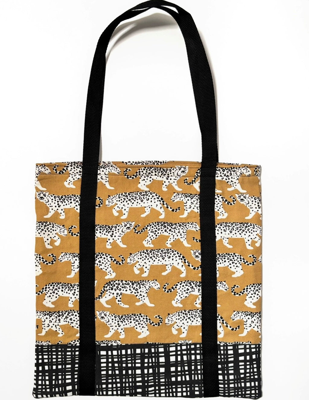 Tote bag with black and white leopard animal pattern on a yellow background, with black and white line pattern bottom and black bag straps
