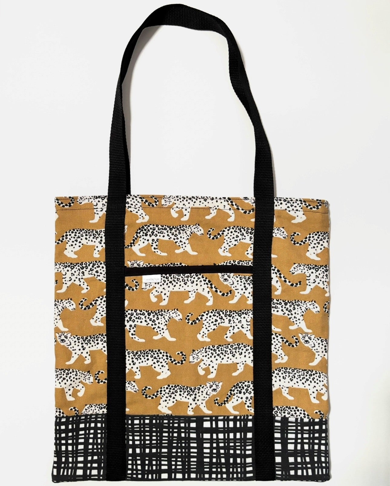 Tote bag with black and white leopard animal pattern on a yellow background, with black and white line pattern bottom and black bag straps