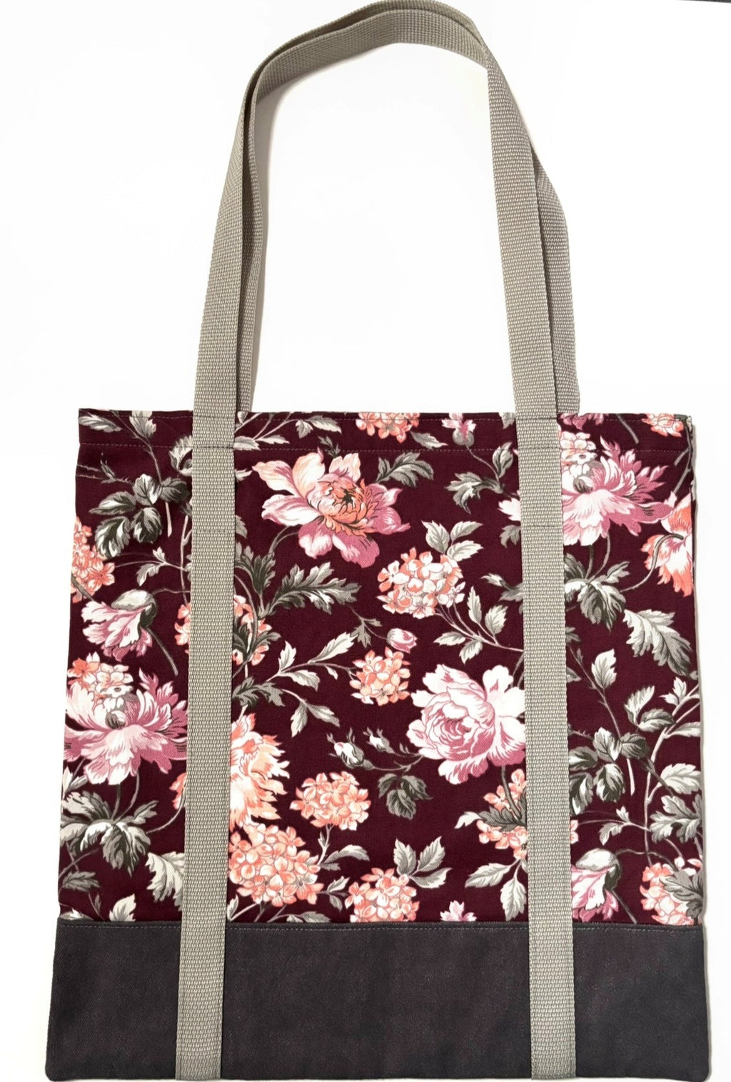 Tote bag with pink floral pattern on a dark red background, with brown bottom and tan bag straps
