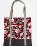 Tote bag with pink floral pattern on a dark red background, with brown bottom and tan bag straps