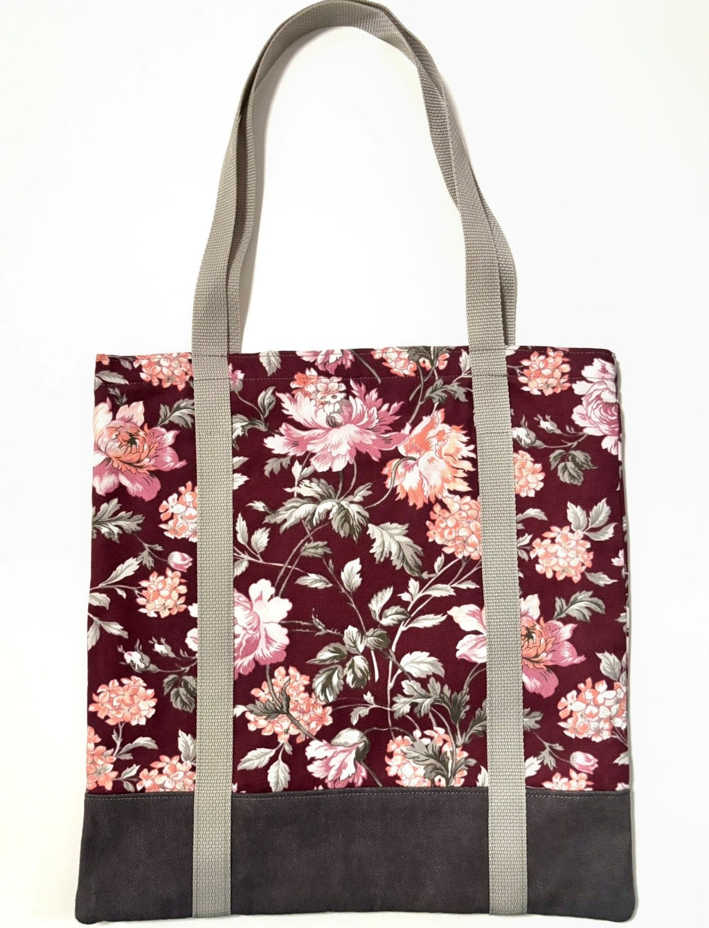 Tote bag with pink floral pattern on a dark red background, with brown bottom and tan bag straps