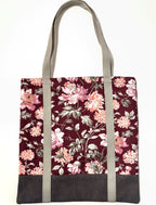 Tote bag with pink floral pattern on a dark red background, with brown bottom and tan bag straps