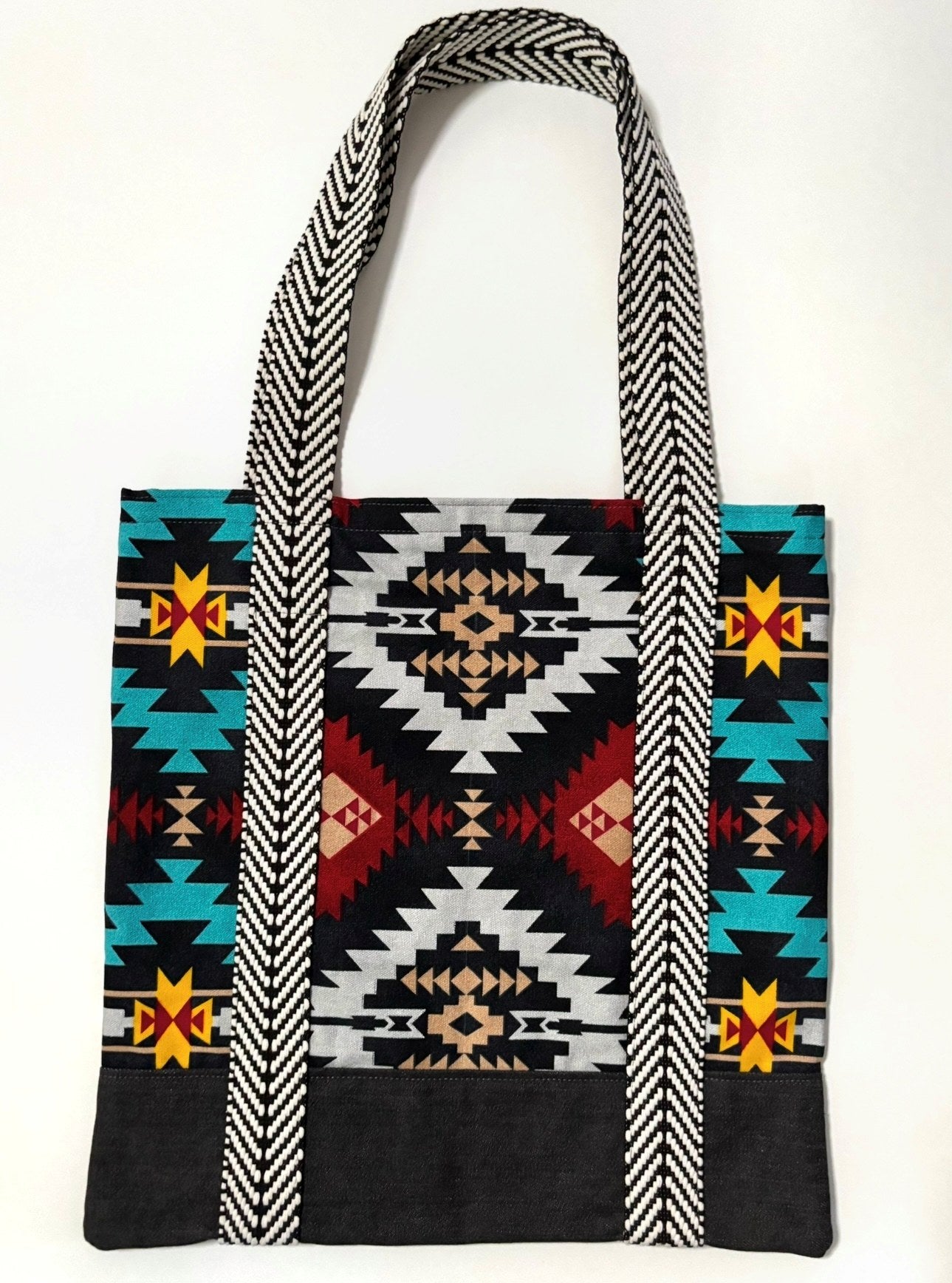 Tote bag with colorful geometric pattern, with black bottom and black and white chevron pattern bag straps