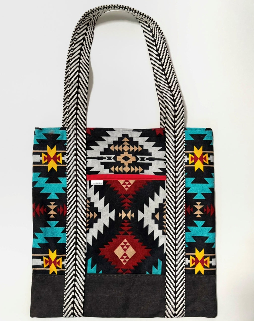 Tote bag with colorful geometric pattern, with black bottom and black and white chevron pattern bag straps