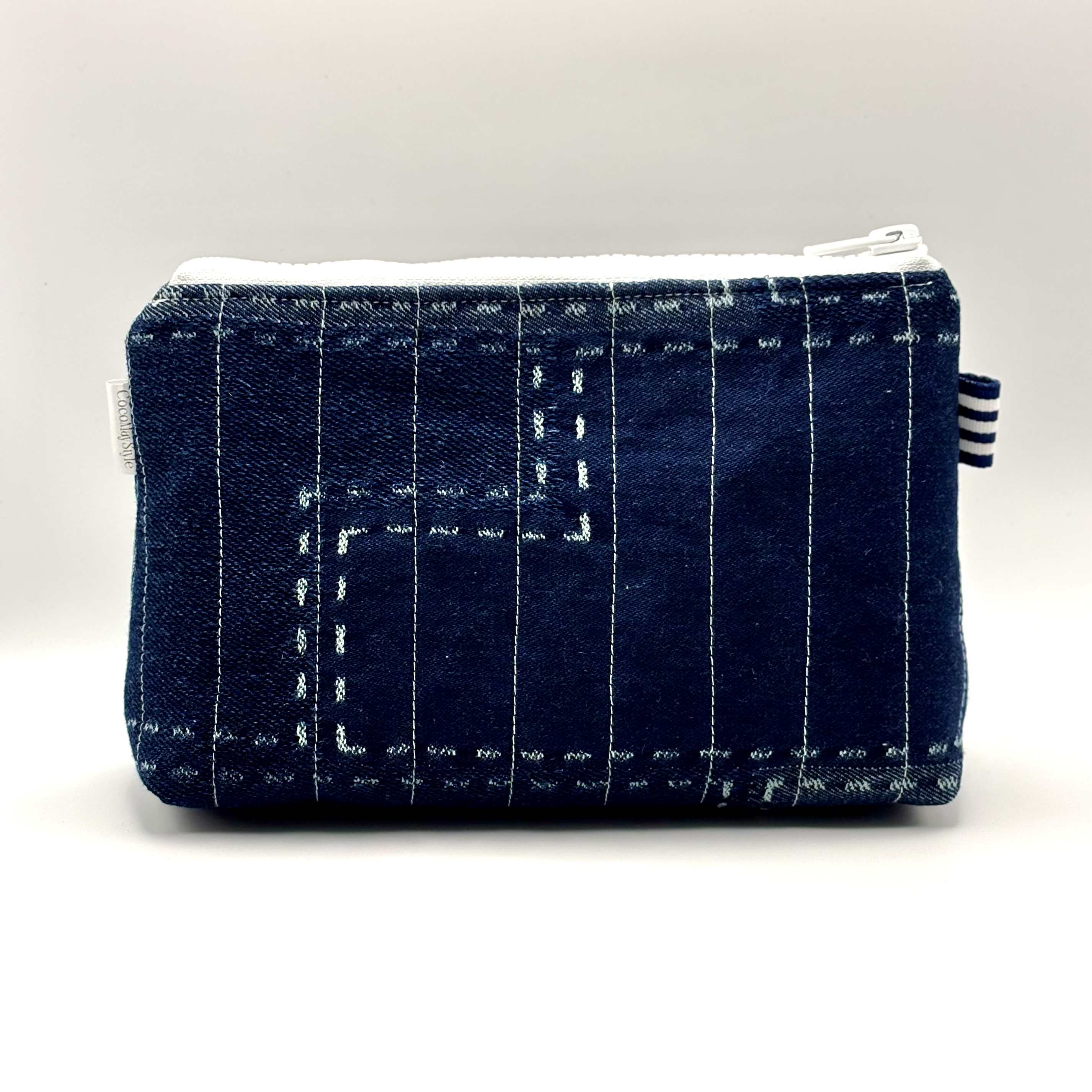 Zipper pouch with white stitching on a dark blue denim background