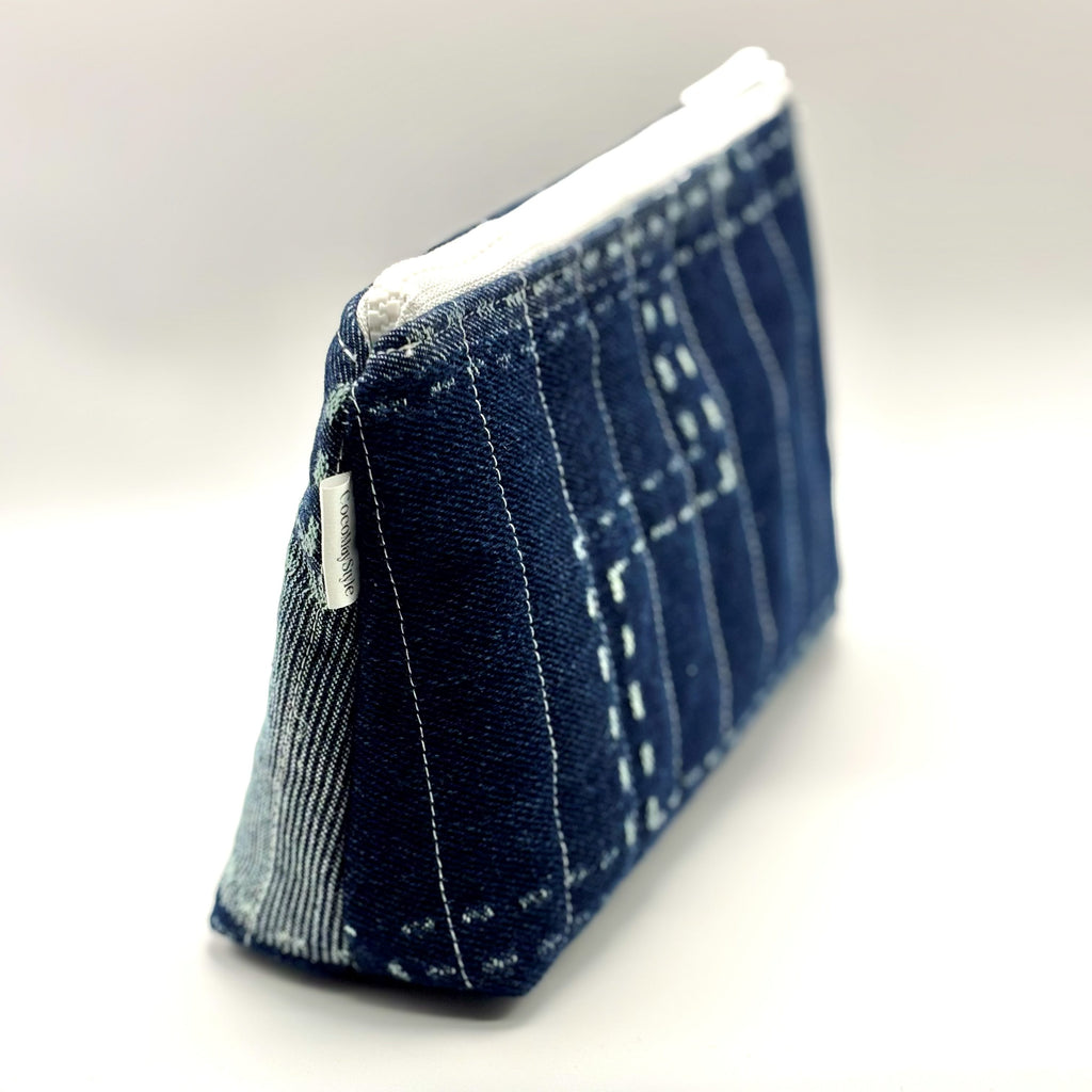 Zipper pouch with white stitching on a dark blue denim background