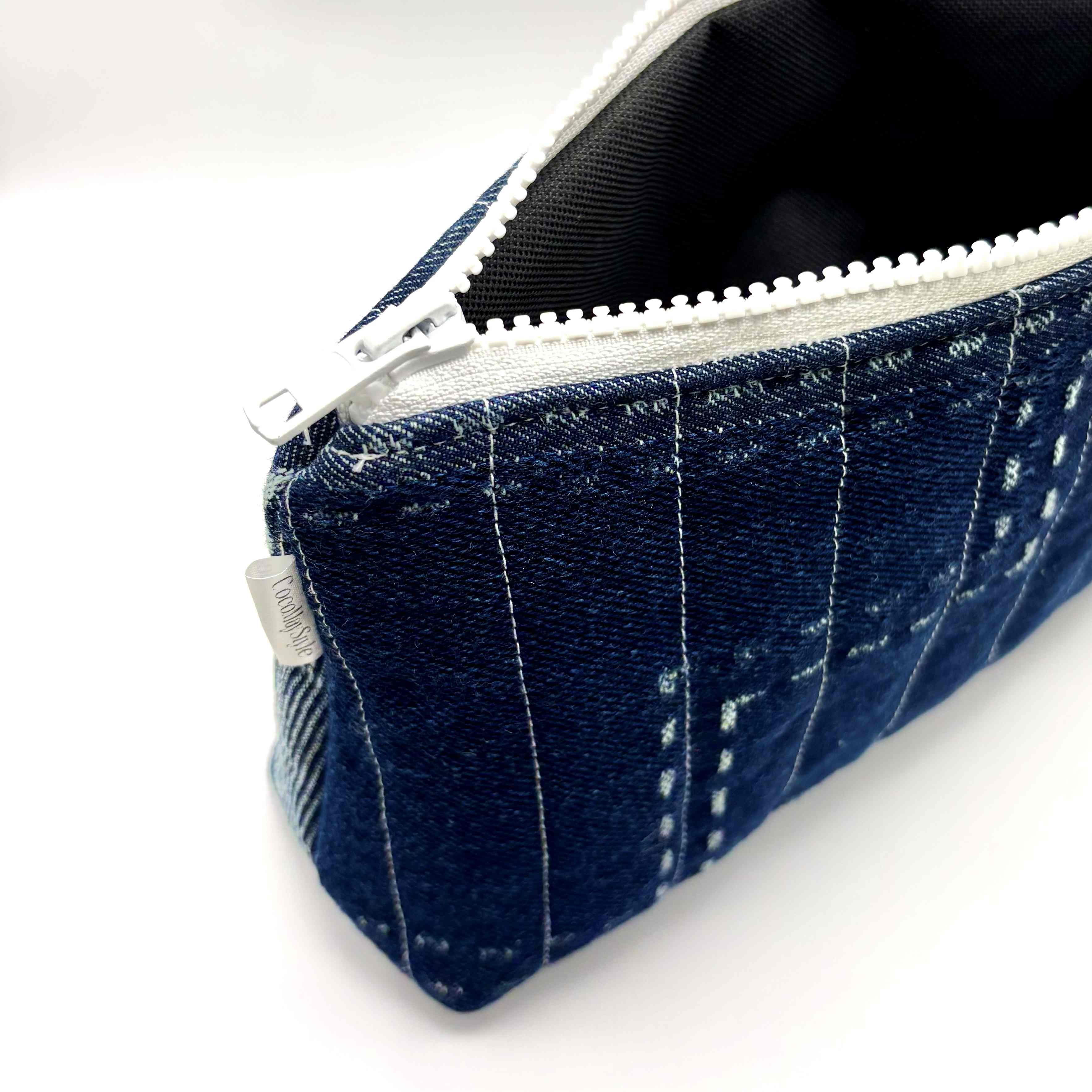 Zipper pouch with white stitching on a dark blue denim background