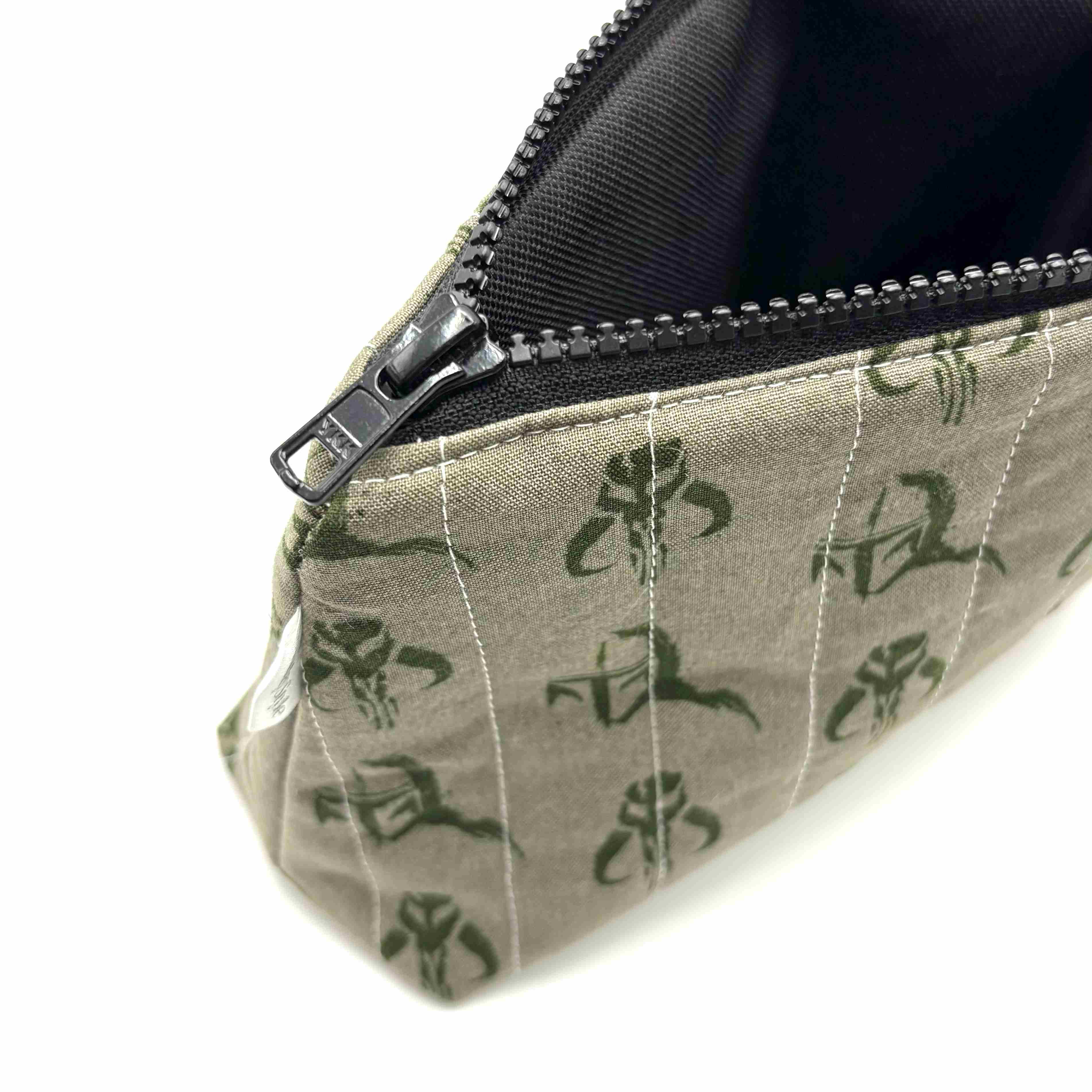 Zipper pouch with a green Mandalorian mudhorn pattern on a tan background