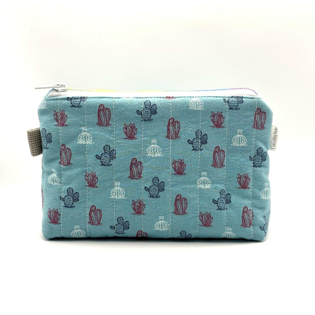 Zipper pouch with a red, white, and blue cacti and succulent pattern on a light blue background