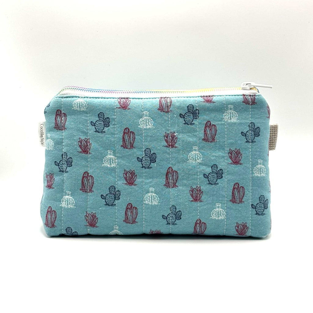 Zipper pouch with a red, white, and blue cacti and succulent pattern on a light blue background
