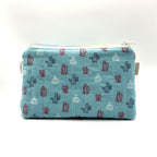 Zipper pouch with a red, white, and blue cacti and succulent pattern on a light blue background