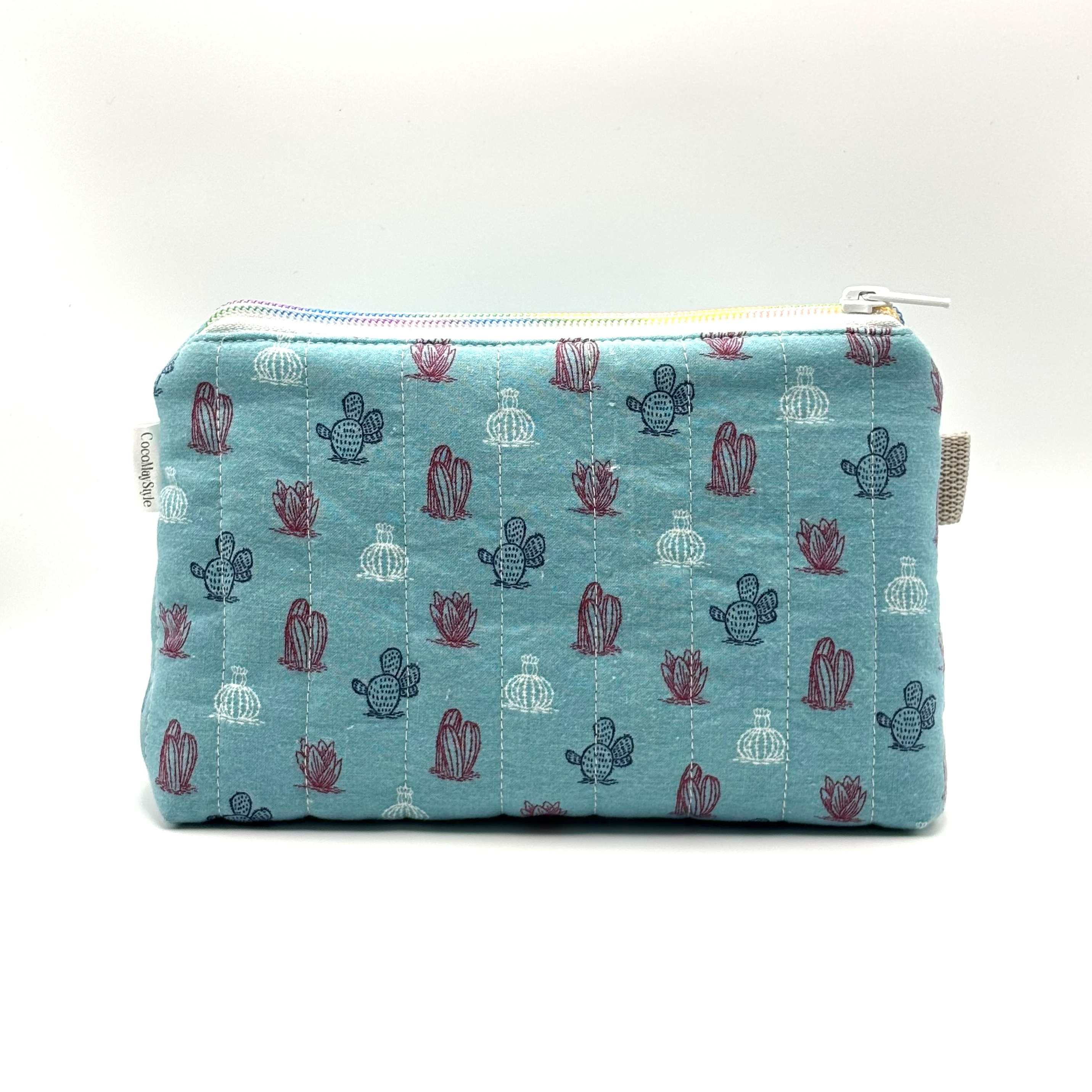 Zipper pouch with a red, white, and blue cacti and succulent pattern on a light blue background